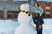 Two people building a giant snowman at UWEC 
