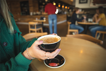 A girl holding a cup of coffee at ECDC in downtown Eau Claire 