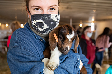 A woman holding a baby goat 