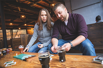 A male/female couple playing Cribbage and drinking beer at the Brewing Projekt 