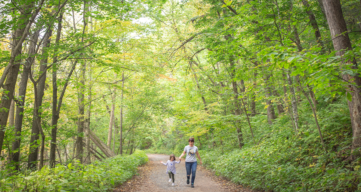 A woman and a young girl walking through greenery at Putnam Park 