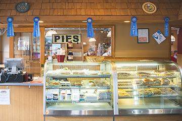 inside the Norske Nook Restaurant, showing the cash register, a glass display filled with vairous pies and desserts, a sign that says 
