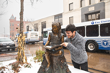 A man interacting with a sculpture in downtown Eau Claire 