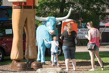 A young girl posing for a photo with Paul Bunyan and Babe at the Wisconsin Logging Museum at Carson Park 