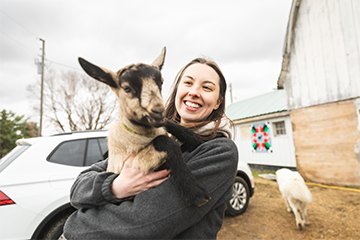 a girl holding a goat kid at Lymett Farms outside of Eau Claire 