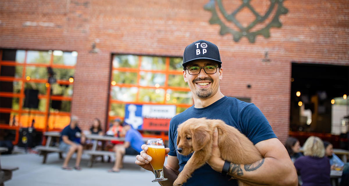 A man holding a beer and a puppy at the Brewing Projekt 
