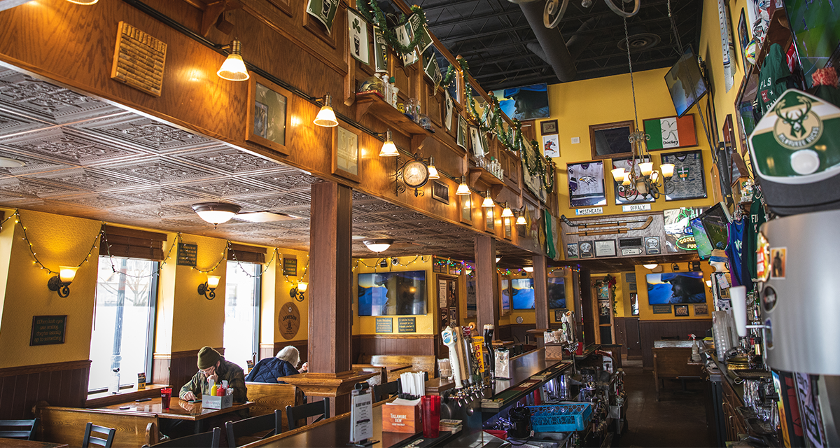 a photo of Dooley's Bar in Eau Claire with Green decorations, an Irish flag, and other sports flags and shirts on the walls 
