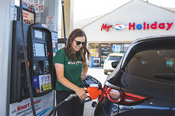 A woman filling up her gas tank at a Mega! Co-Op Holiday gas station 