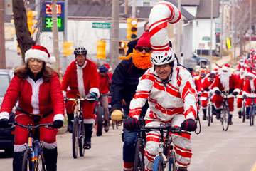 People riding bikes dressed in Santa costumes 