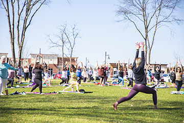 a large group of people doing yoga outside in River Prairie Park at River Prairie Festival 