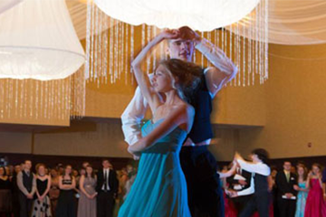 a man wearing a suit and woman wearing an evening gown twirling and dancing in each other's arms at a ball 