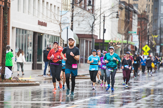 a group of runners running down the streets of Eau Claire at the Eau Claire Marathon 
