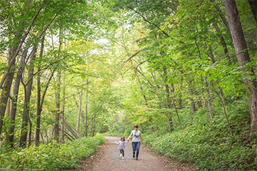 Mom and daughter walking through greenery at Putnam Park 