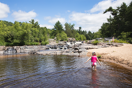 A young girl wading through the water at Big Falls County Park 