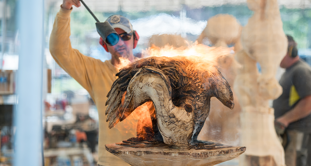 A man making a sculpture with fire at the Chainsaw Championship 