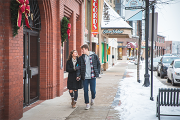 Man and woman couple walking down street holding hands on a date in Eau Claire 