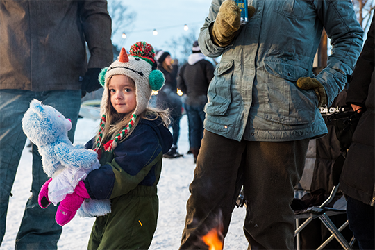 A young girl holding a stuffed animal at an outdoor winter event in River Prairie 