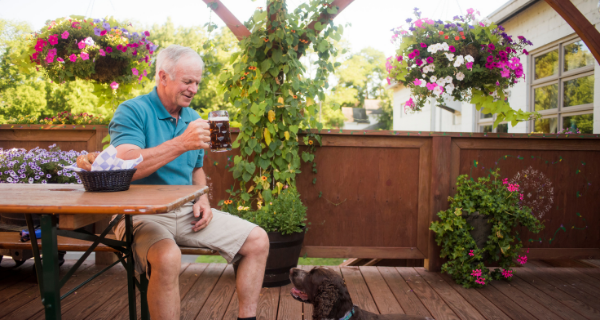 A man sitting at the beer garden at Lazy Monk drinking beer with a dog by his side 
