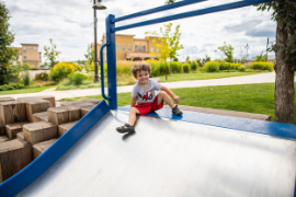 Little boy sliding down playground slide at River Prairie Park 