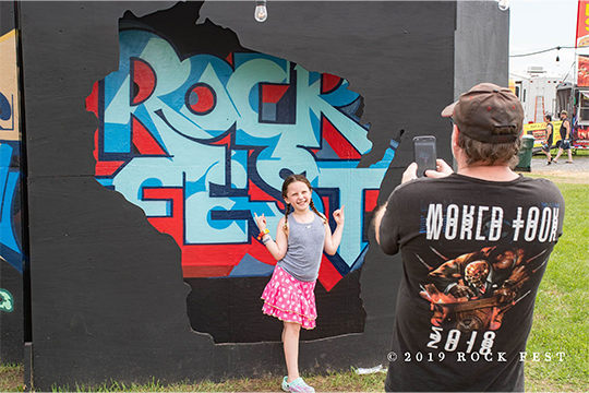 A young girl posing in front of a photo opportunity at Rock Fest 