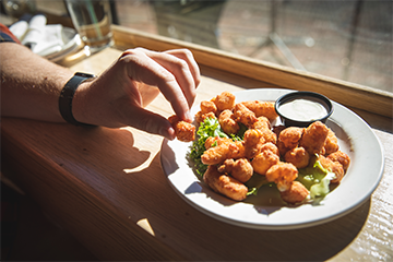 A hand reaching for cheese curds at Mogie's Pub 