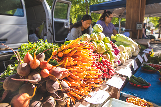 a table filled with colorful, fresh vegetables and produce at the Eau Claire Farmers Market 