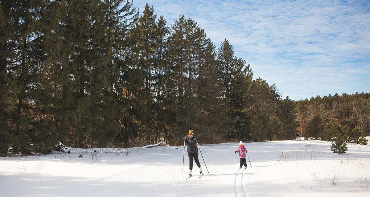 An woman and a young girl cross country skiing at Lowes Creek County Park 